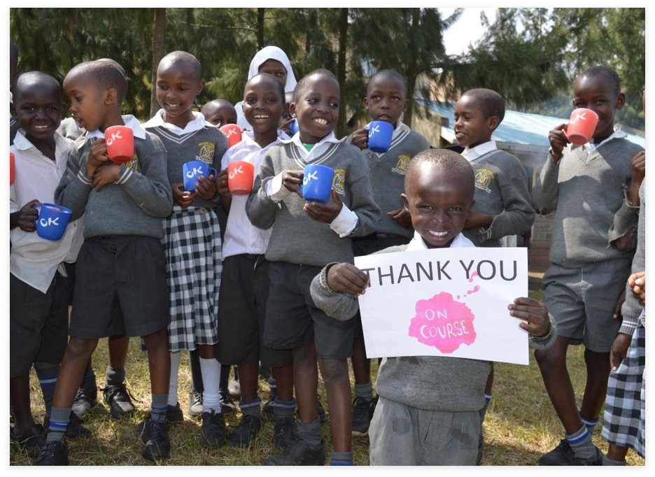 Primary school students holding OnCourse cups and a thank-you sign